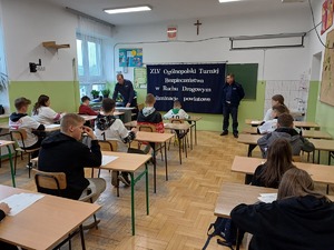 Uczestnicy turnieju piszą test wiedzy w sali.