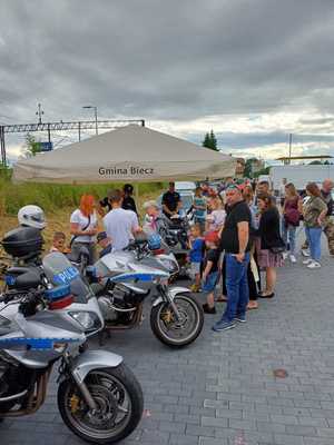 Osoby stojące przy stoisku policji, obok stoją policyjne motocykle.