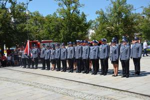 Stojący na rynku pododdział Policji z pocztem sztandarowym.