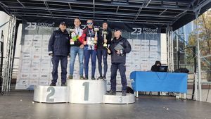 Zwcięzcy maratonu i dwóch policjantów ubranych w mundury stoi na podium.