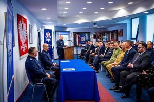 Na auli do zebranych gości i policjantów. którzy siedzą, przemawia Komendant Powiatowy Policji w Gorlicach. Przy stole siedzi Zastępca Komendanta Wojewódzkiego Policji w Krakowie.