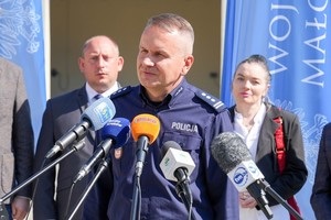 Komendant Wojewódzki Policji w Krakowie wypowiada się do mikrofonów, za nim stoi wojewoda małopolski.