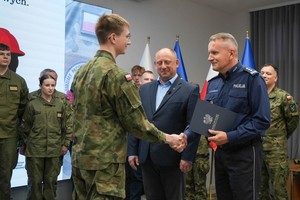 Komendant wręcza osobie mianowanie do sztabu młodych mundurowych.