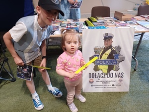 Dwoje dzieci przy plakacie policjanta na stoisku Policji.