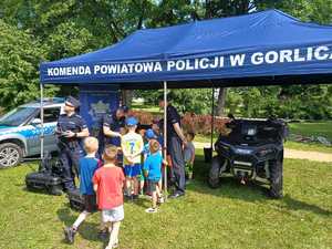Dzieci z policjantami koło policyjnego namiotu.