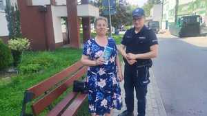 Policjant przekazuje ulotkę informacyjną osobie na ulicy.