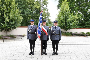Poczet sztandarowy policji stoi przed wejściem do kościoła.