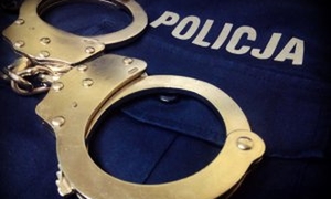Na bluzie z napisem policja leżą policyjne kajdanki.