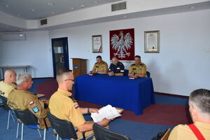 Przy stole na auli siedzi komendant powiatowy policji  i  2 komendantów ze straży pożarnej.