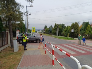 Przez przejście przechodzą dzieci, obok przejścia stoją policjanci.