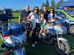 Dwóch policjantów i uczestnicy pikniku na policyjnych motocyklach.