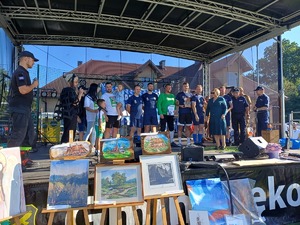 Na scenie stoi drużyna która wygrała turniej piłkarski i są im wręczane upominki przez Komendanta Miejskiego Policji z Nowego Sącza i Komendanta Powiatowego Policj z Gorlic