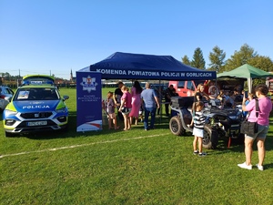 Stoisko komendy powiatowej policji w Gorlicach, obok którego stoi radiowóz i policyjny quad.