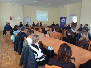 Na sali siedzą osoby. Policjant omawia prezentacje, która jest wyświetlana.
