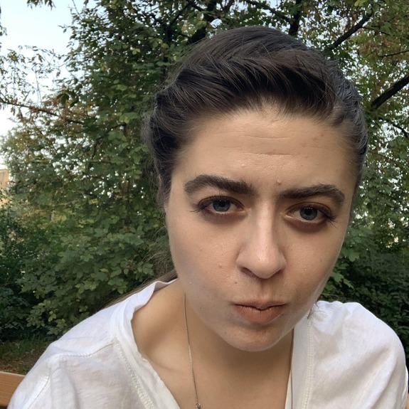 Młoda dziewczyna z czarnymi włosami na tle zieleni.