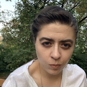 Młoda dziewczyna z czarnymi włosami na tle zieleni.