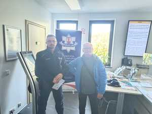 Policjant przekazuje starszemu mężczyźnie w placówce ZUS materiały profilaktyczne.