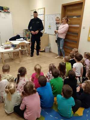 Policjant w sali przed siedzącymi dziećmi.