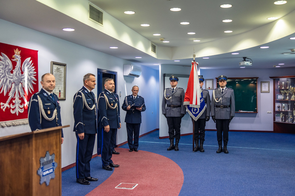 Komendanci i stojący obok poczet sztandarowy.