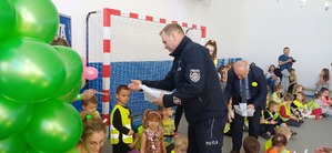 Policjant wręcza dzieciom odblaski.