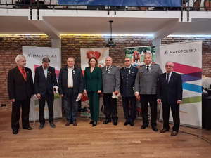 Trzech policjantów którzy odebrali odznaki honorowych dawców krwi stoi razem z innymi osobami.