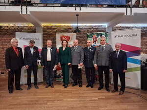 Trzech policjantów którzy odebrali odznaki honorowych dawców krwi stoi razem z innymi osobami.