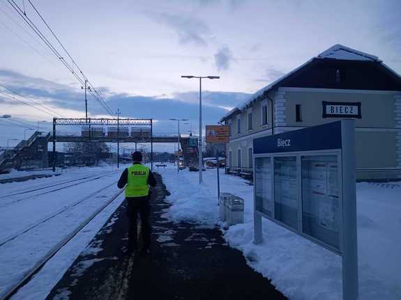 Jeden policjant stoi na peronie stacji kolejowej.