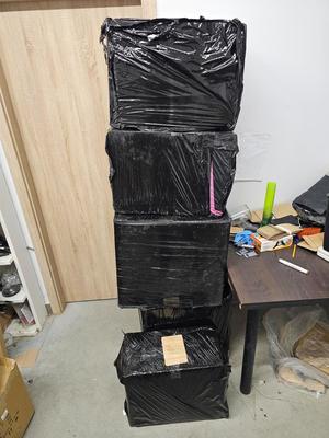 Kilka pudełek stojących na sobie zawiniętych w czarną folię.