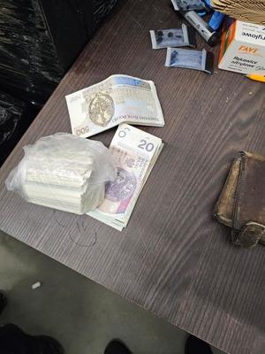 Na stoliku leży portfel i plik banknotów.