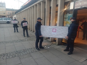Policjanci wnoszą do pomieszczenia paczki, które przywieźli.