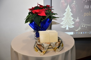 Na stoliku stoi kwiat gwiazda betlejemska, a w koszyczku leżą opłatki.