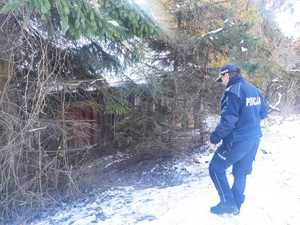 Policjant podchodzi pod stary budynek.