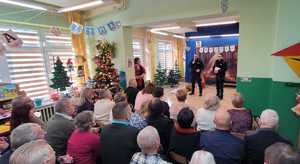 Dwóch policjantów  prowadzi prelekcję do seniorów w przedszkolu podczas dnia babci i dziadka.