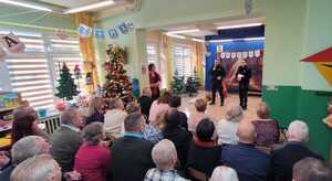 Dwóch policjantów  prowadzi prelekcję do seniorów w przedszkolu podczas dnia babci i dziadka.