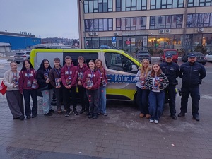 Policjanci i wolontariusze WOŚP przy policyjnym radiowozie.