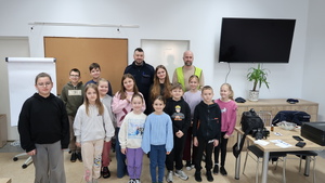 Policjant z dziećmi w sali. obok na stole walizka i aparat fotograficzny technika kryminalistyki