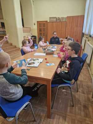 Policjant z dziećmi siedzi przy stole.