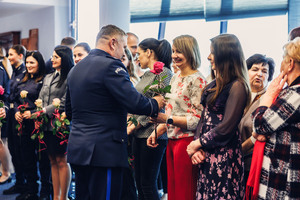 Komendant wręcza róże paniom.