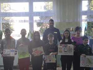 Policjant i kilku uczestników konkursu stoją i trzymają przed sobą swoje prace plastyczne.