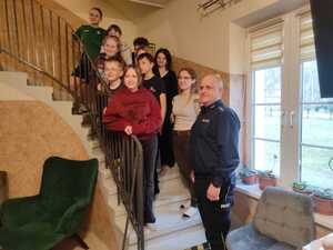 Kilkanaścioro dzieci i policjant stoją na schodach.