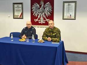 Policjant i funkcjonariusz straży granicznej siedzą przy stole.