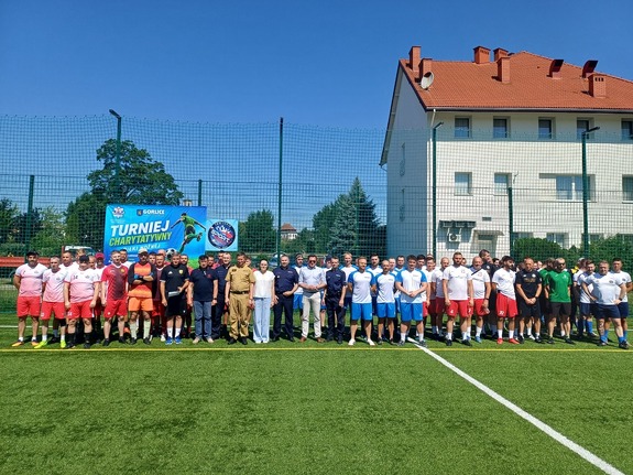 Drużyny stoją w rzędach na boisku.