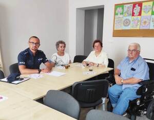 Policjant z kilkoma seniorami siedzi przy stole.