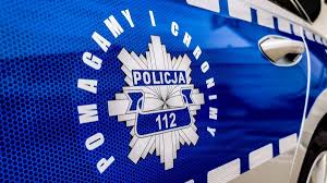 Na drzwiach policyjnego radiowozu policyjna gwiazda z napisem Policja 112. Wokół gwiazdy napis pomagamy i chronimy