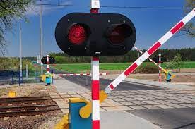 Przejazd kolejowy z zamykającymi się zaporami i migającymi na czerwono światłami.