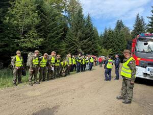 Dowódca akcji wydaje polecenia do stojącego przed min pododdziału policji i wojska.