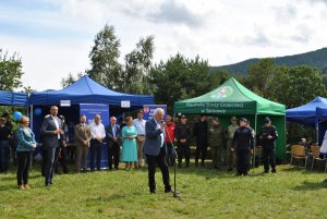 Mężczyzna stoi na środku i przemawia do zebranych gości