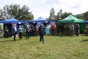 Funkcjonariusz Policji przemawia do zebranych gości przed stoiskami służb mundurowych