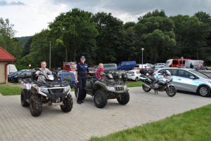 Funkcjonariusz Policji stoi przy dwóch kładach na których siedzą dzieci.