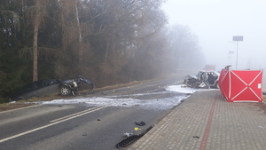 Dwa pojazdy ze zniszczonymi i porozrzucanymi elementami przodów pojazdów stoją na drodze.